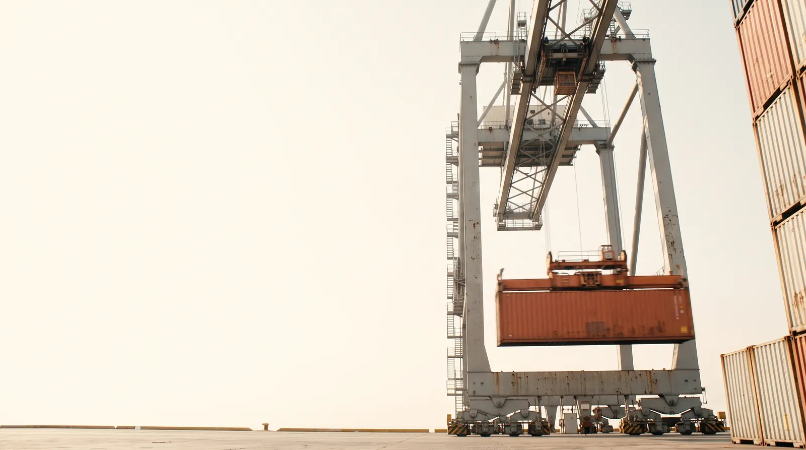 Gantry cranes over stacked containers at a Mexican port terminal in warm morning haze